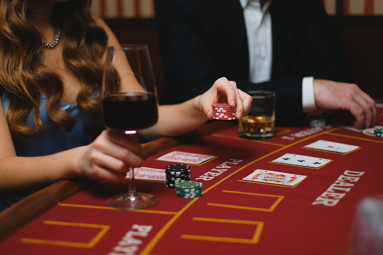 A poker game with drinks, featuring wine and chips on a casino table.
