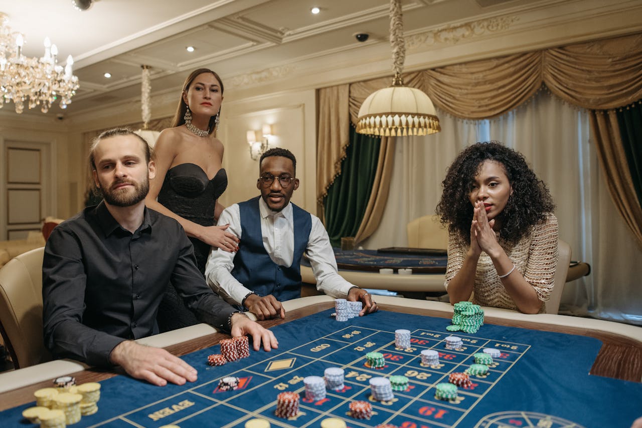Four adults enjoying a game of roulette in a luxurious casino setting.