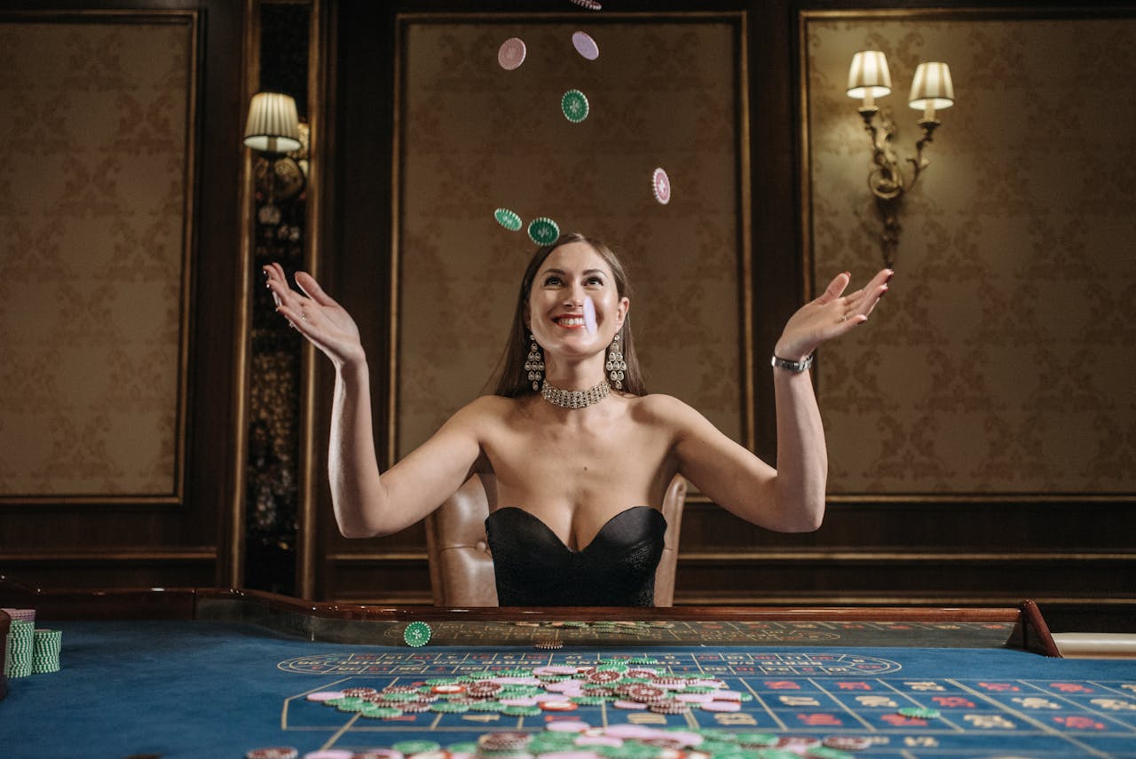 our-services-1 A smiling woman tosses casino chips up in an elegant gaming room, exuding joy.